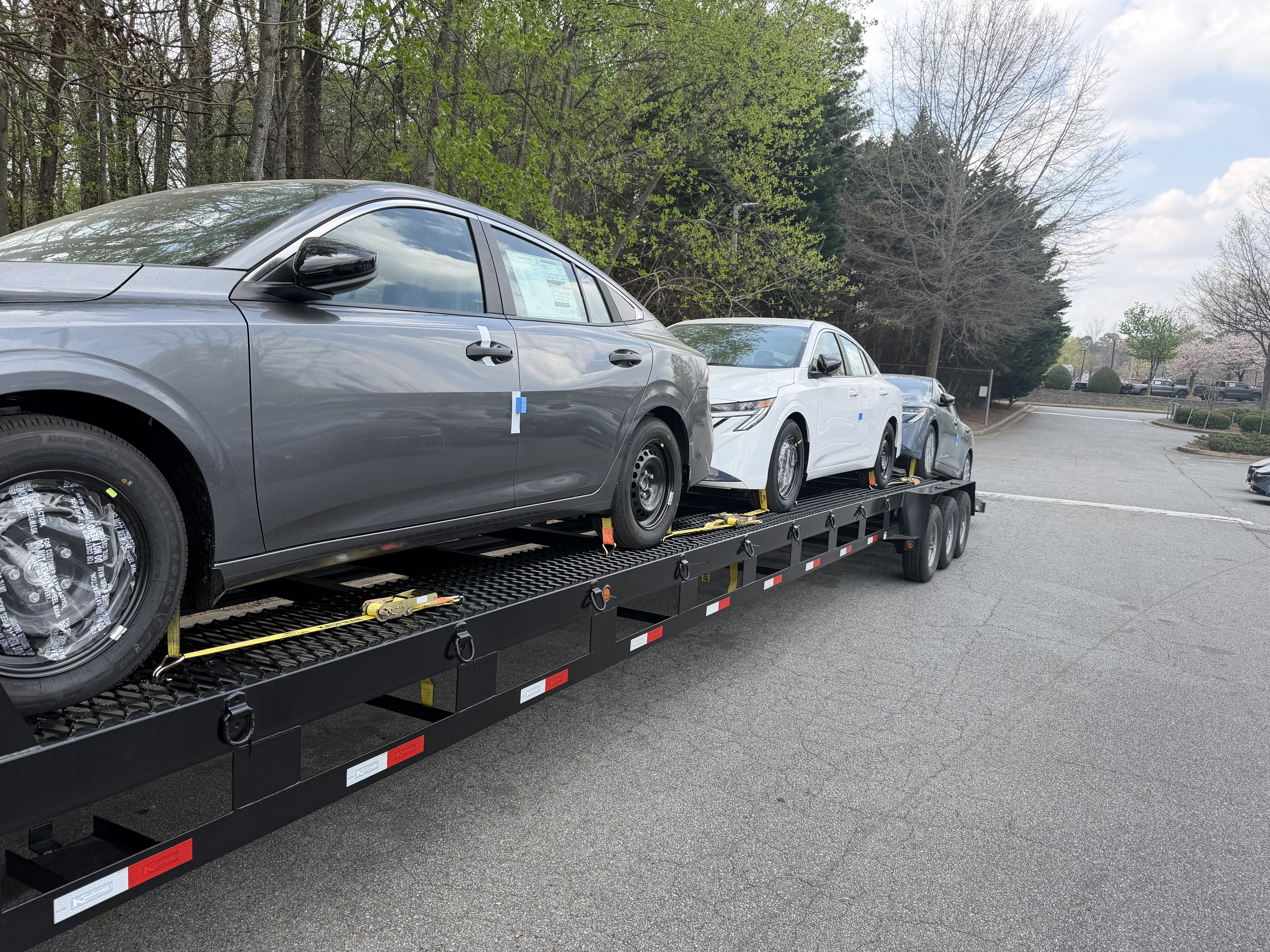 New Nissan sedans secured on an open transport trailer